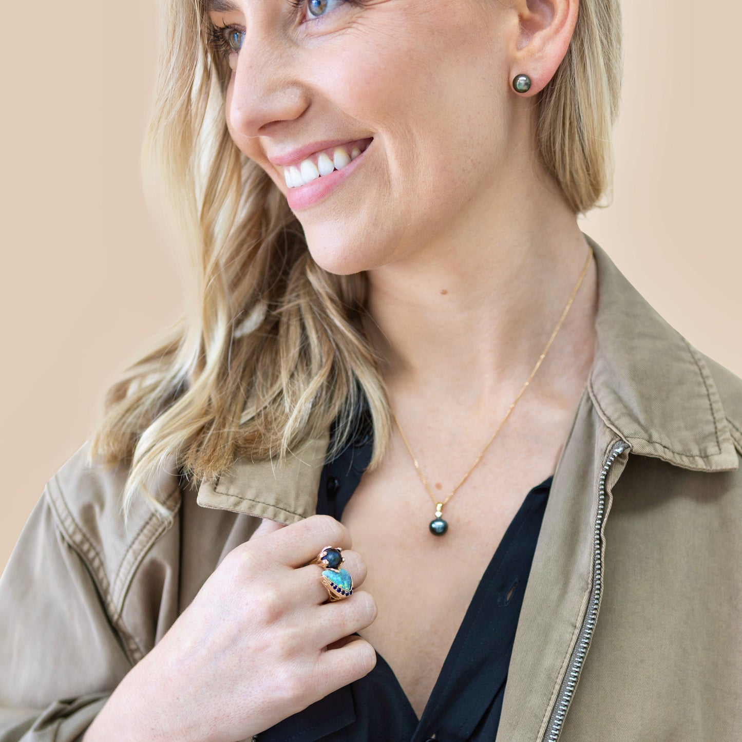 Model wearing 10mm black Tahitian pearl stud earrings in 14ct yellow gold; lifestyle portrait showing size and luster.