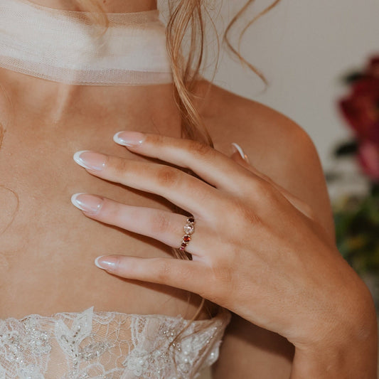 Bride wearing a five-stone colour-change zircon engagement ring with garnet and pink sapphire accents.
