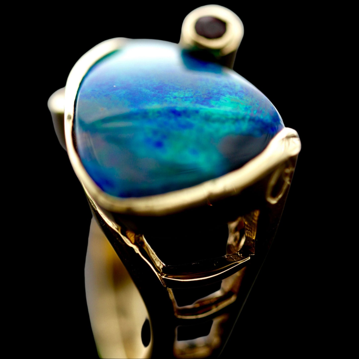 Top view macro of domed opal and openwork gallery of the 18ct yellow gold ruby and diamond cocktail ring.