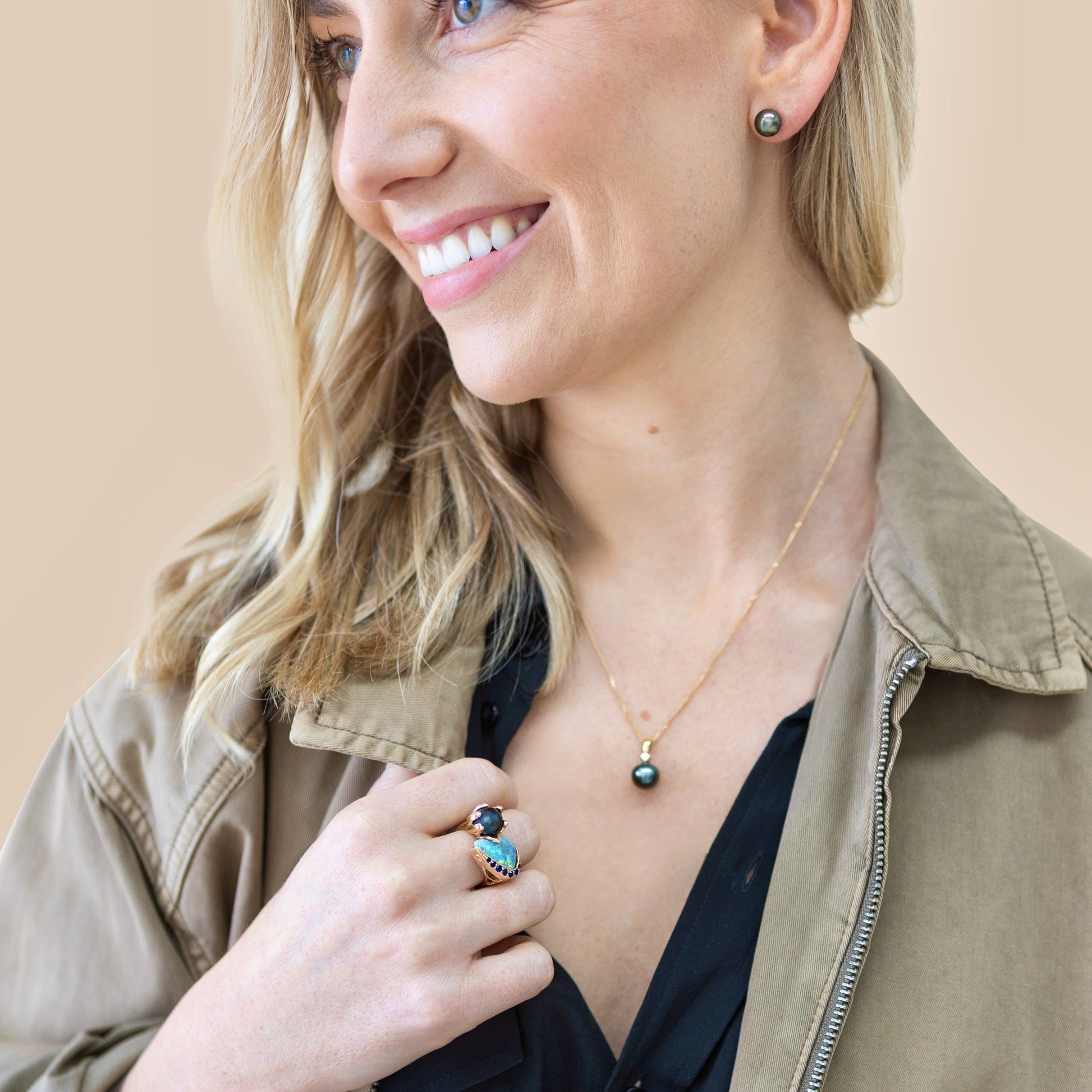 Model wearing 10mm black Tahitian pearl stud earrings in 14ct yellow gold; lifestyle portrait showing size and luster.