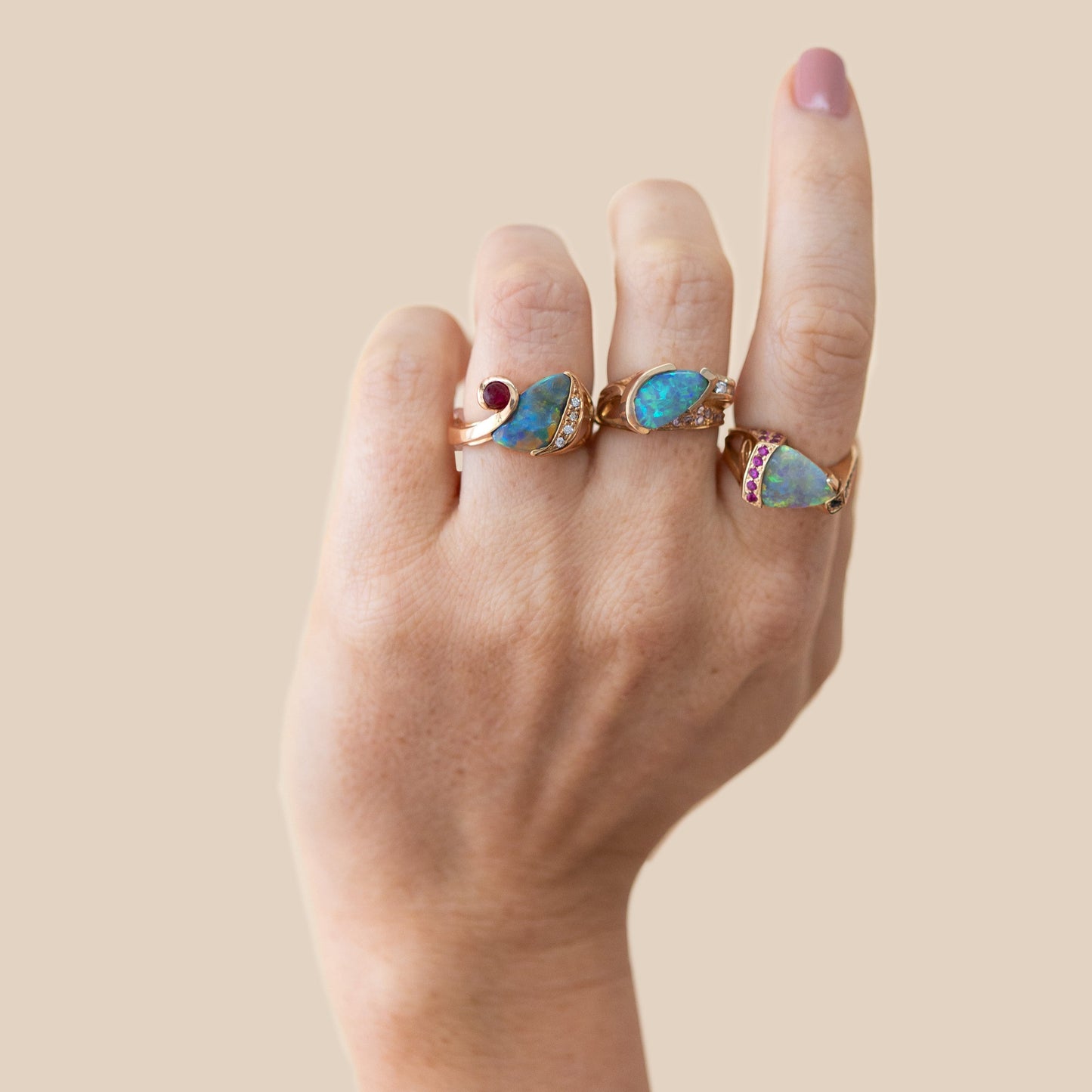 Stacked opal rings on hand featuring the 2.75ct black opal, diamond and ruby ring.