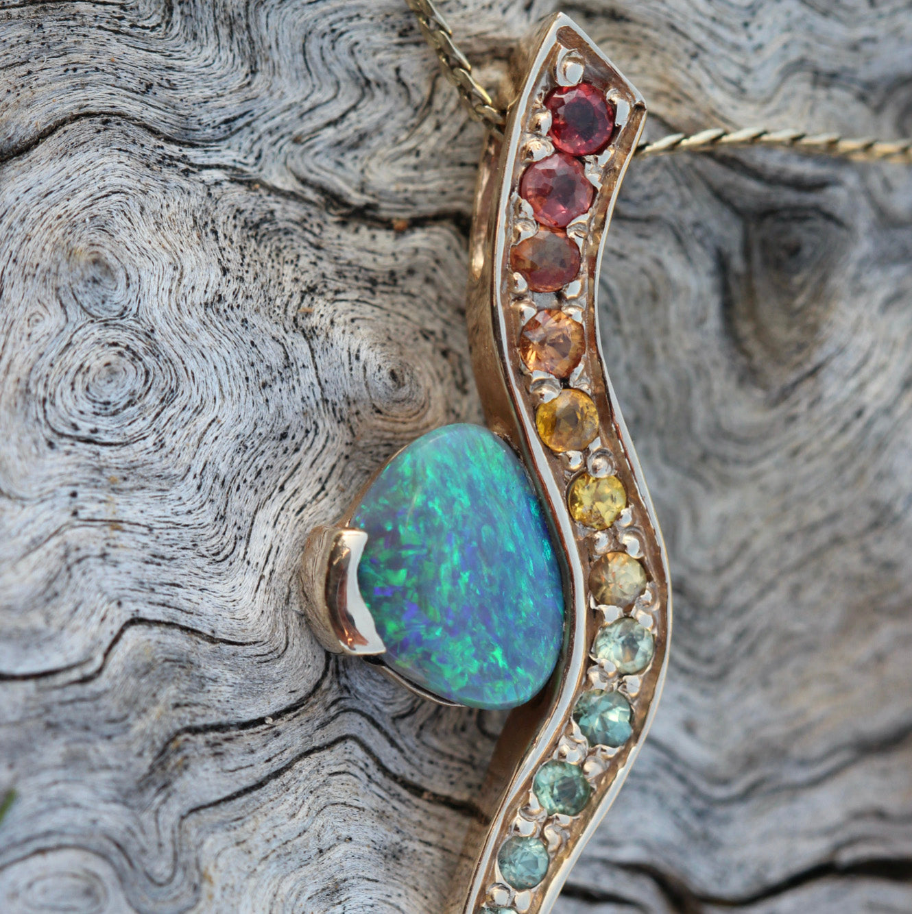 Close-up of the opal’s play-of-colour with graduated rainbow sapphires set along the wave.