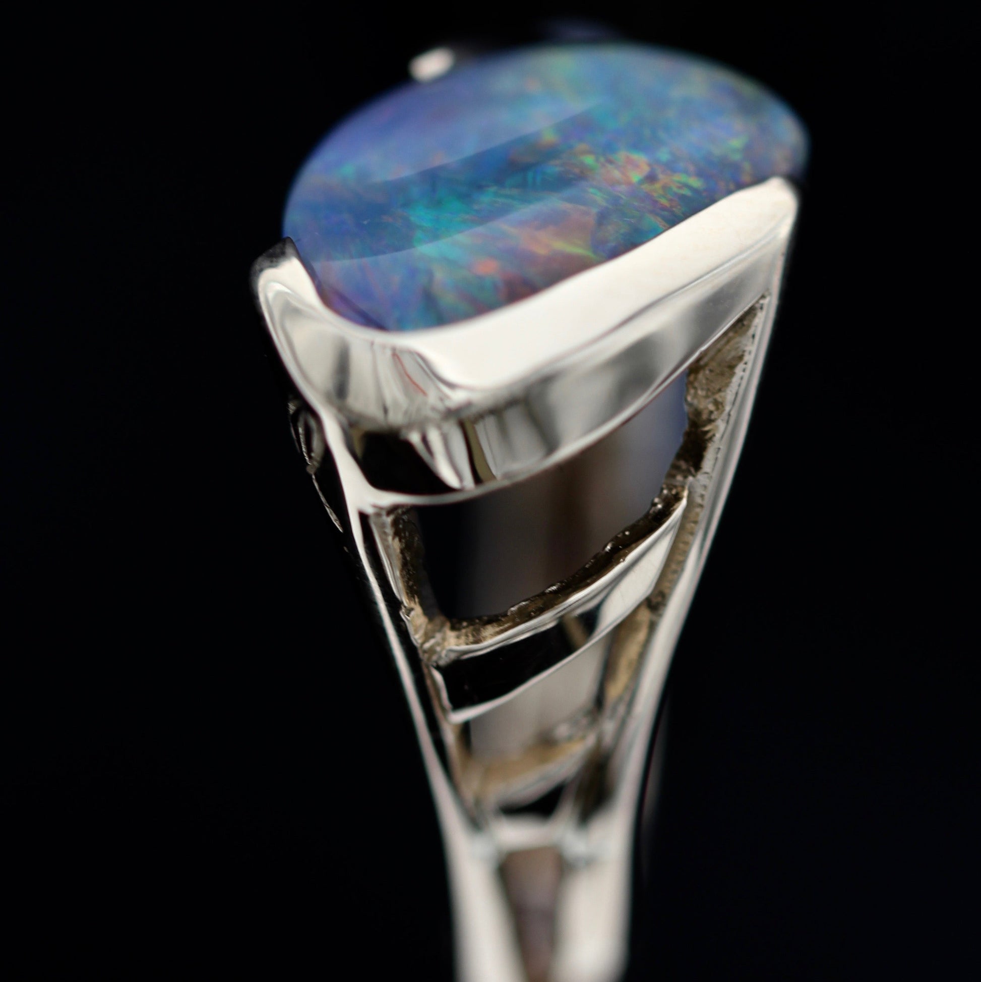 Macro detail of sapphire channel and diamond triangle on a Lightning Ridge black opal statement ring, 18ct yellow gold setting.