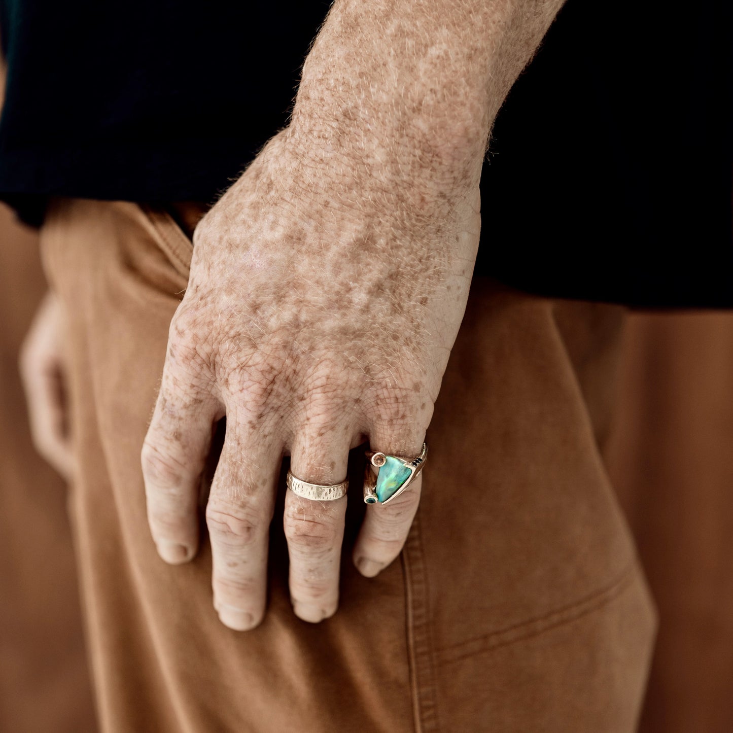 Man wearing the 4.77ct Lightning Ridge opal ring with blue and orange sapphires in 14ct yellow gold.