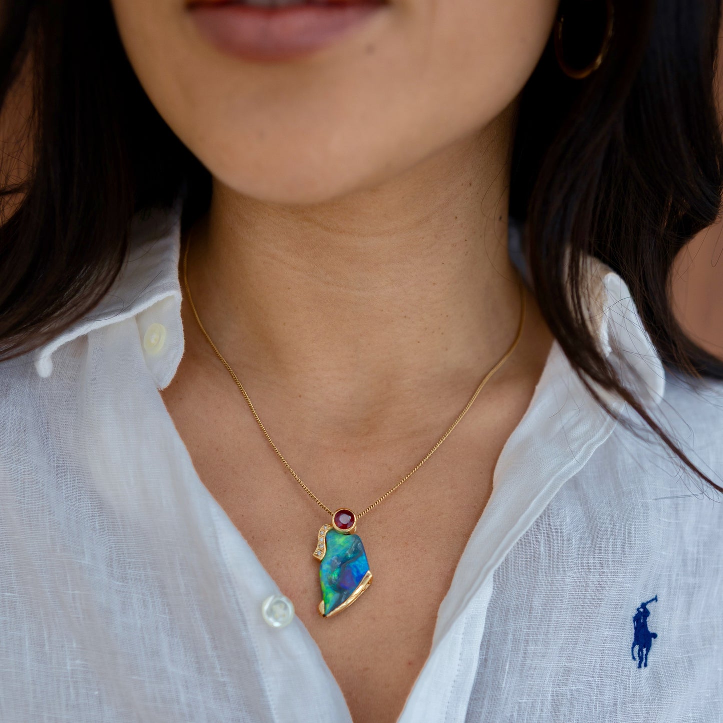 Opal, ruby and diamond pendant in 14ct yellow gold shown on model’s neck for scale and wear.