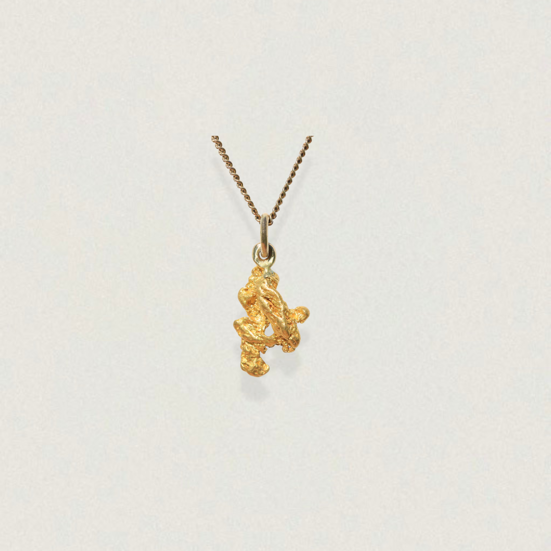 Natural gold nugget pendant in 18K with polished bail on neutral background