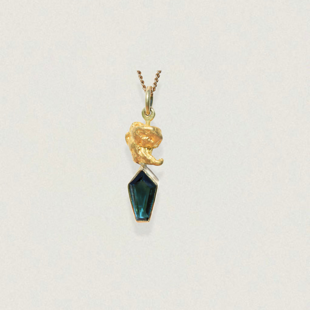 Australian parti sapphire kite-cut pendant topped with a natural gold nugget, shown on chain against a light background.