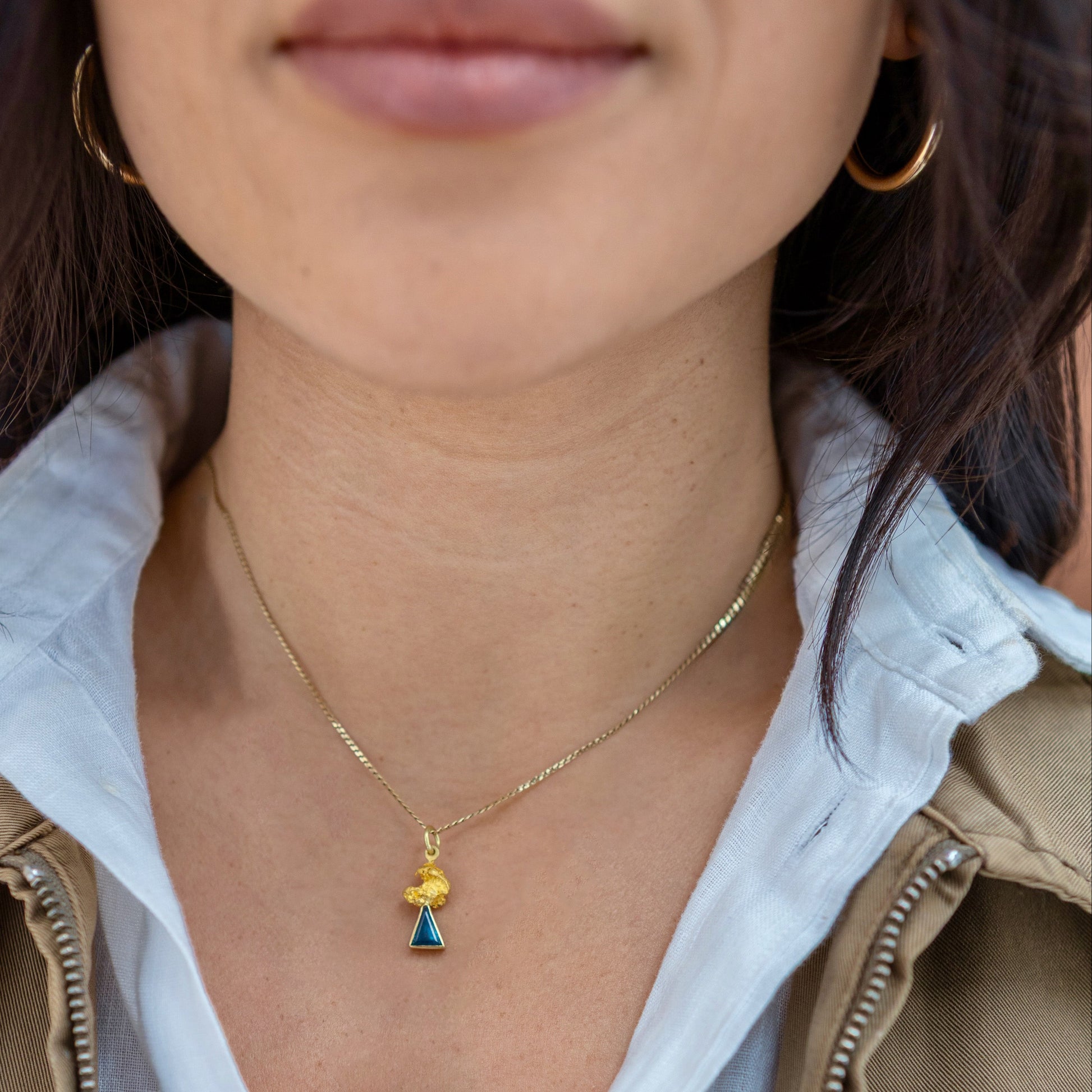 Model wearing an Australian parti sapphire triangle pendant with a natural gold nugget (92–98% pure gold) on a gold chain.