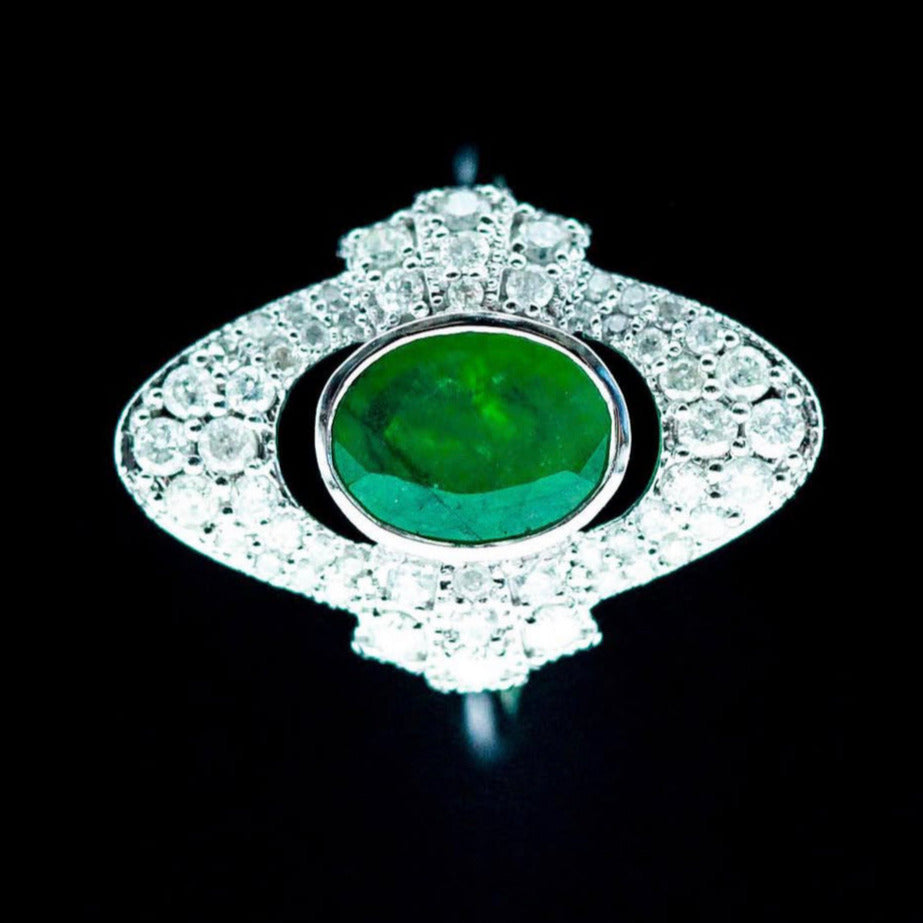 Macro of 1.26ct oval emerald cabochon with pavé diamond halo and geometric shoulders in white gold.