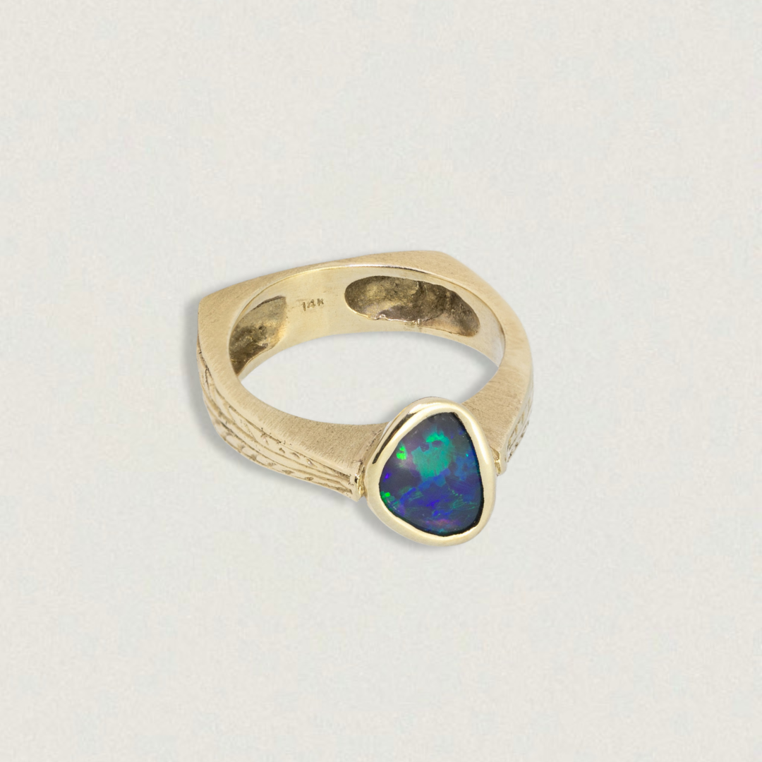 0.70ct Lightning Ridge black opal ring in 14k yellow gold, bezel-set, on white background.