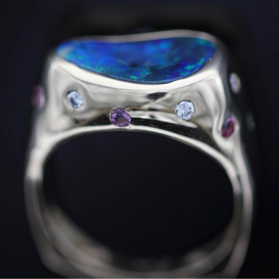 Side profile of 18ct gold ring band featuring flush-set diamonds and pink sapphires beneath a Lightning Ridge black opal.
