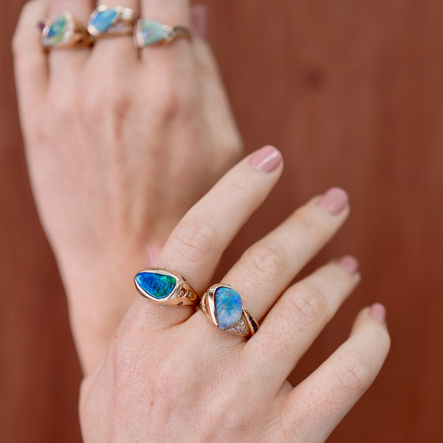 Lifestyle close-up of black opal, diamond and pink sapphire ring in 18ct gold worn on hand while holding a cocktail.