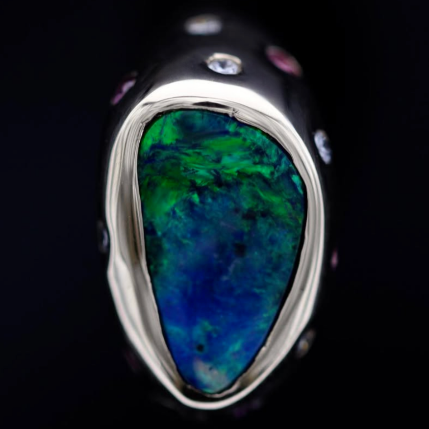 Macro view of Lightning Ridge black opal cabochon showing blue-green play-of-color in 18ct gold bezel.