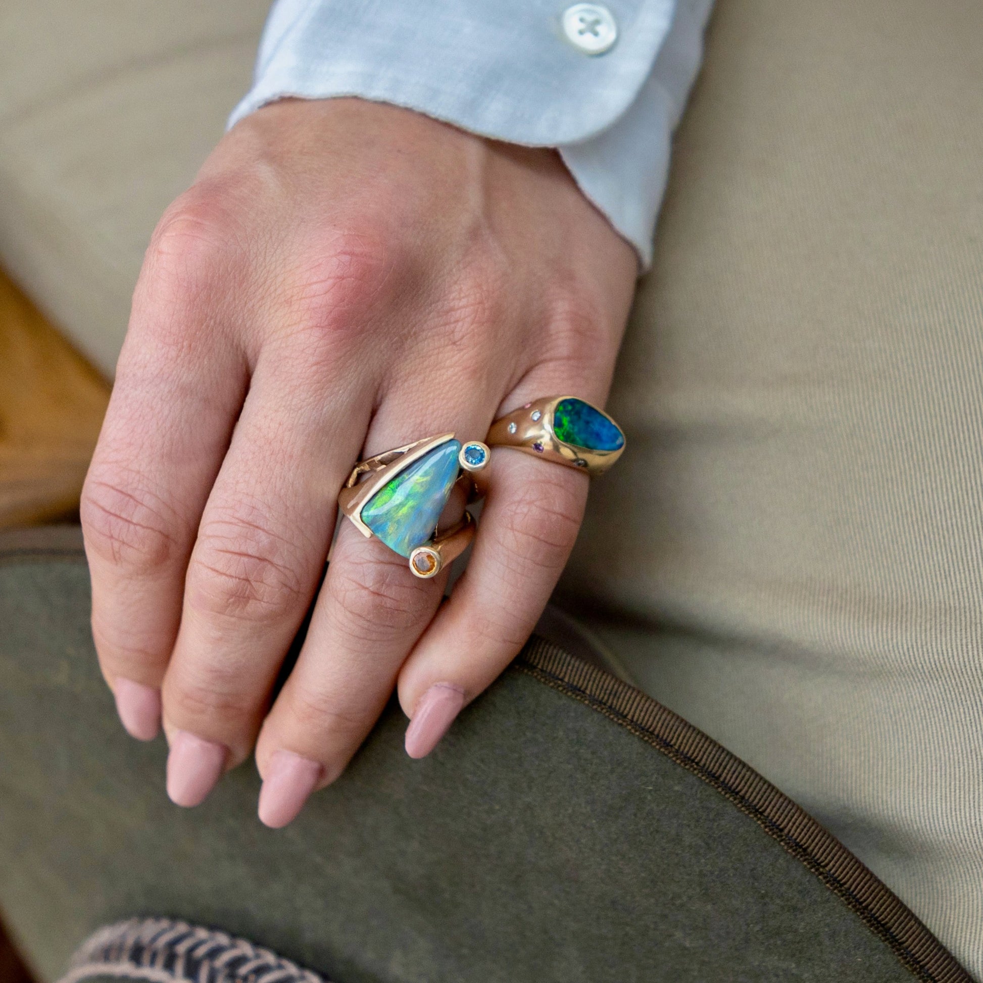 Black opal ring in 18ct gold styled with other opal rings on hand to show scale and stackability.