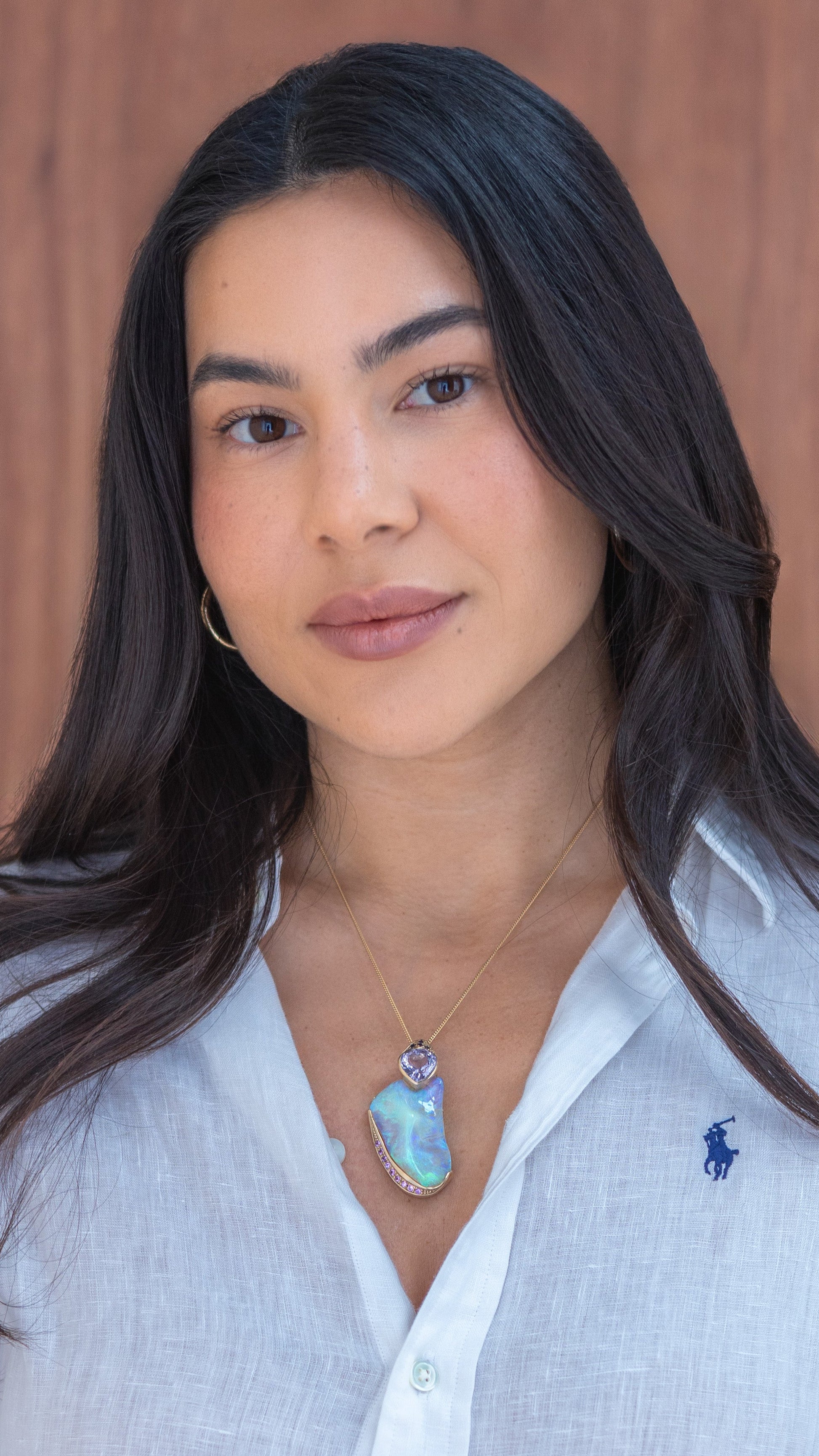 Model wearing a yellow-gold Lightning Ridge crystal opal pendant with amethyst and sapphire accents on a fine chain.