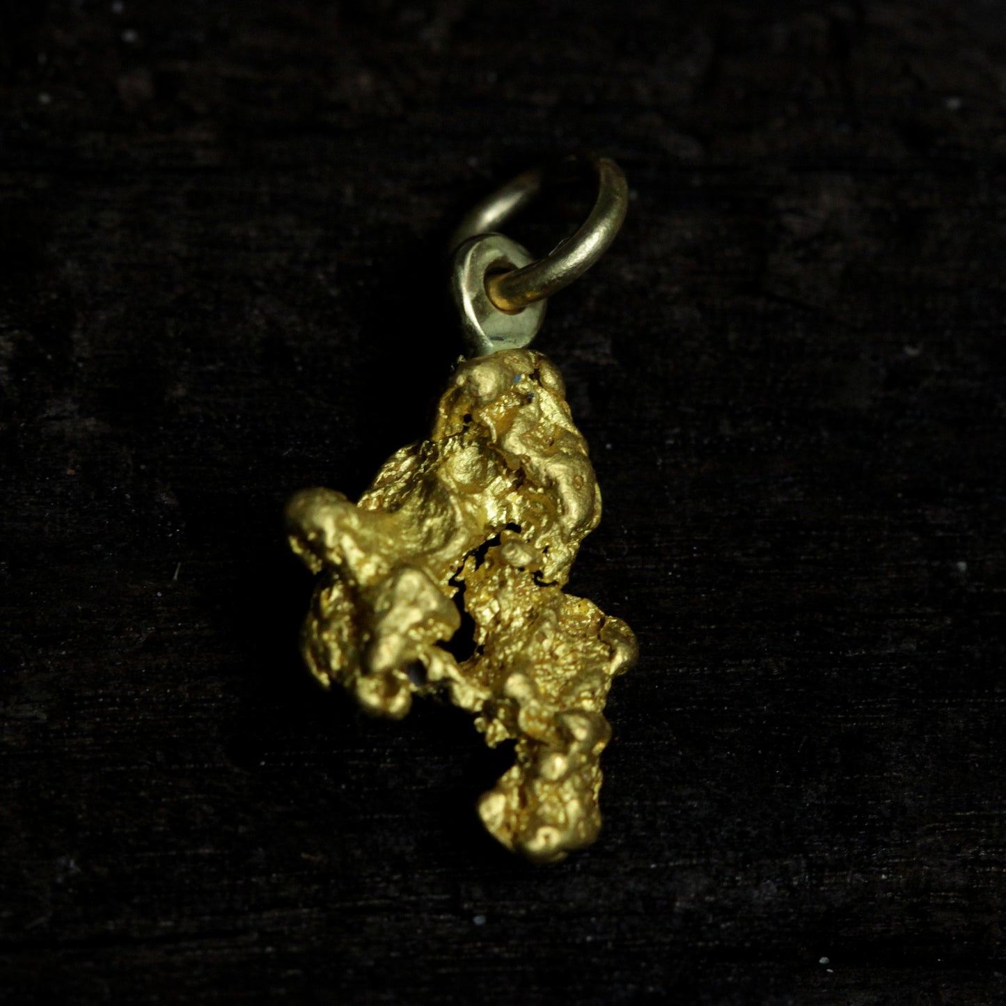 Close-up of natural Palmer River Australian gold nugget pendant, ~2 g, raw texture on dark background.