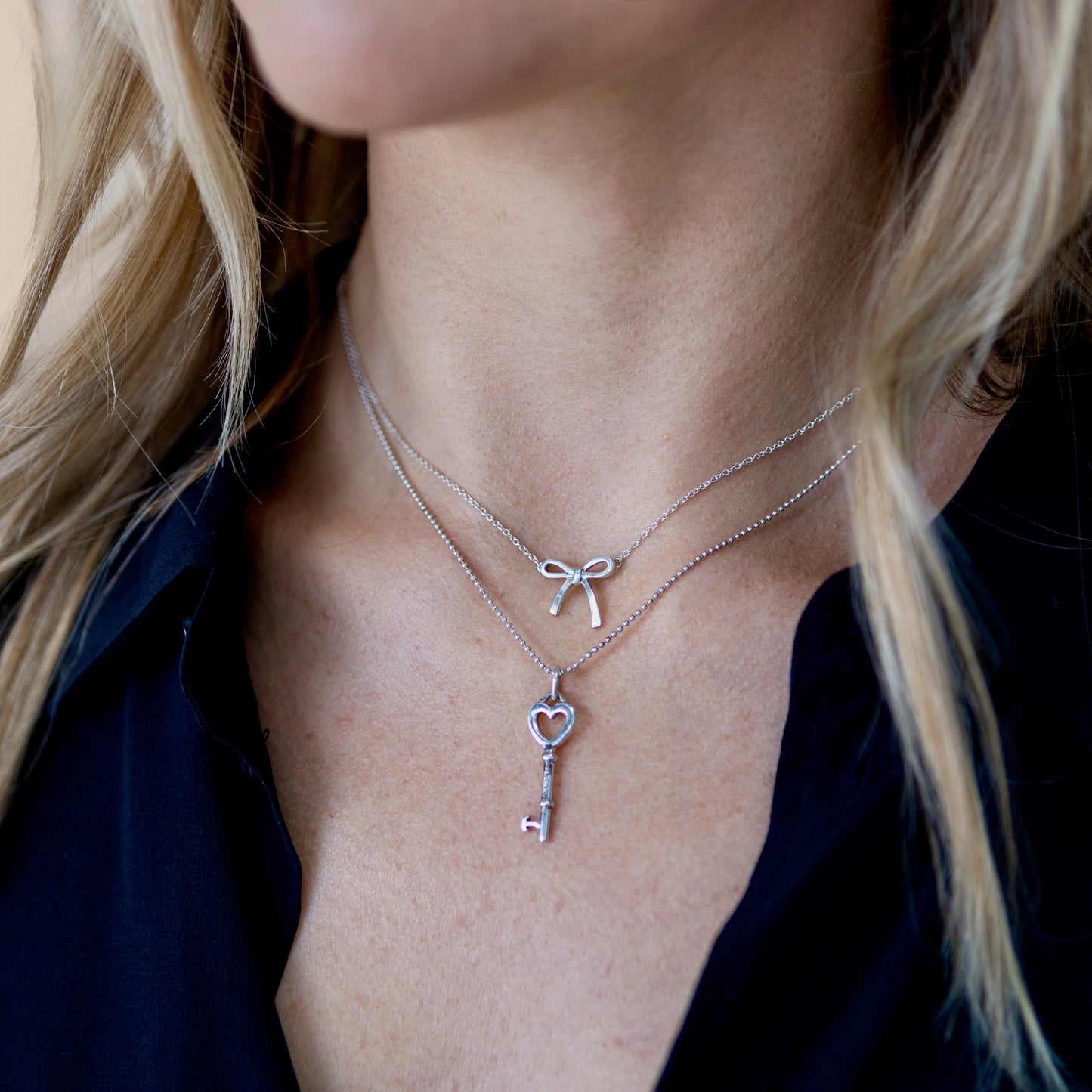 Layered look on model wearing vintage Tiffany & Co. Elsa Peretti Bow sterling-silver pendant above a heart key charm
