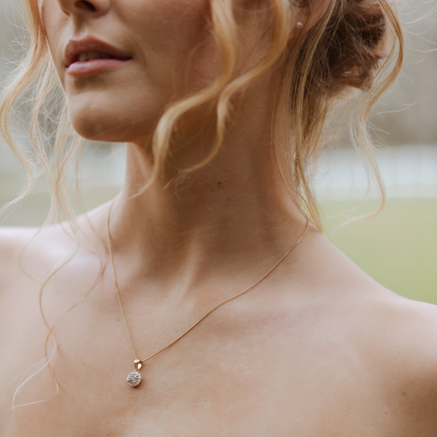 Diamond halo pendant in 14ct rose gold worn on model’s neck