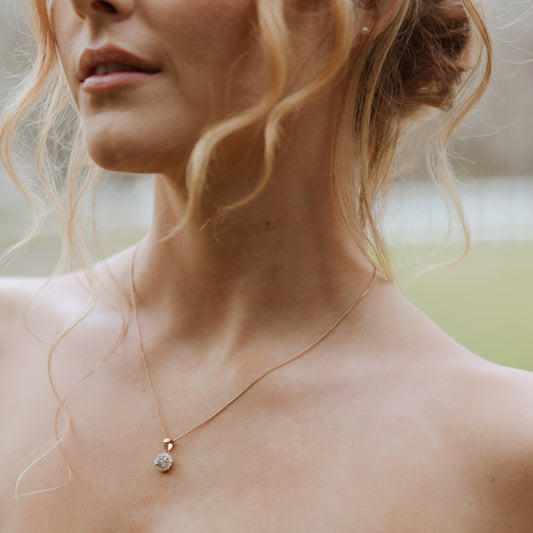 Diamond halo pendant in 14ct rose gold worn on model’s neck