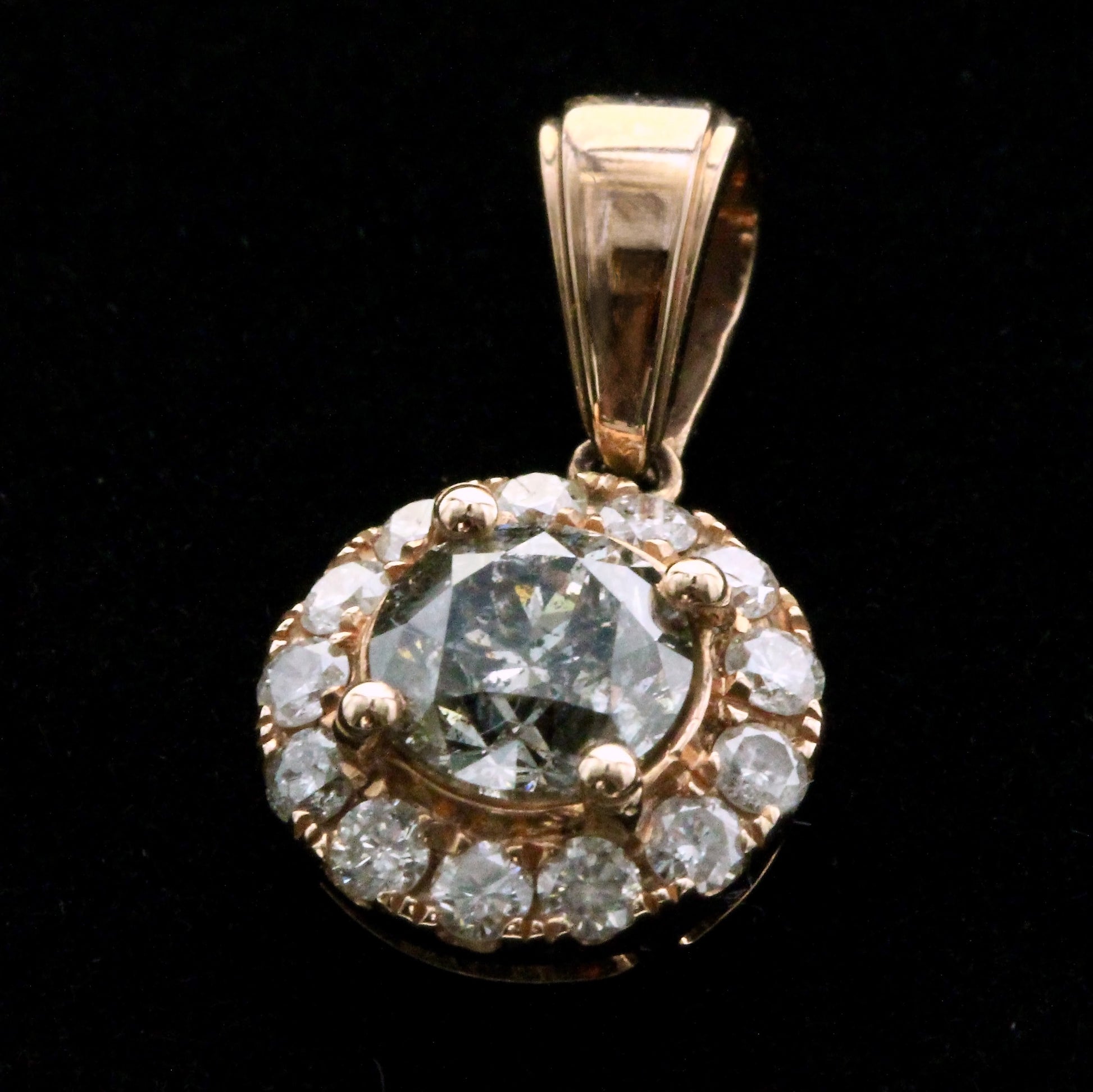 Close-up of vintage diamond halo pendant showing rose gold setting and round brilliant stones