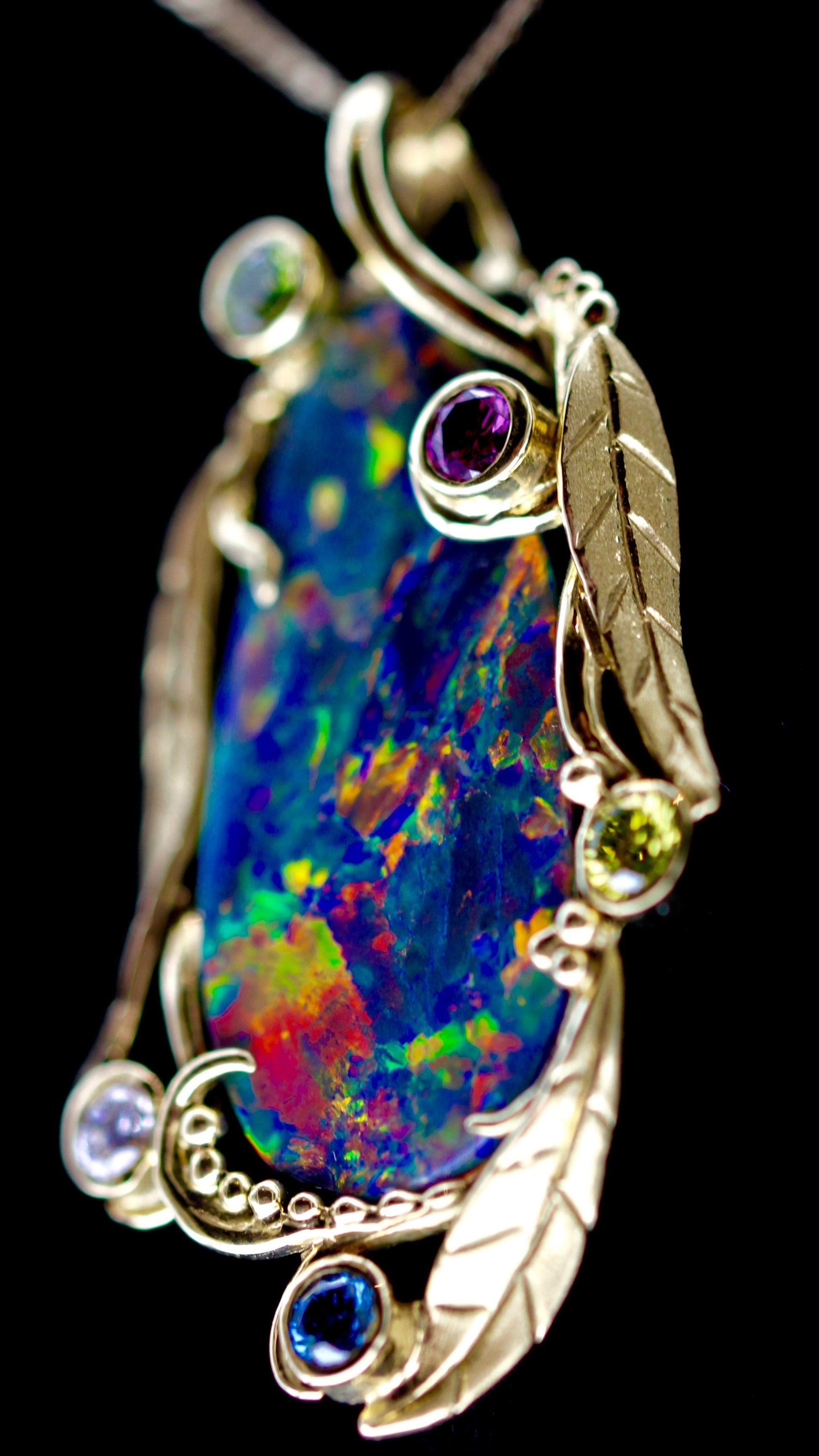 Macro detail of the pendant’s top section showing leaf engraving, beadwork and accent stones.