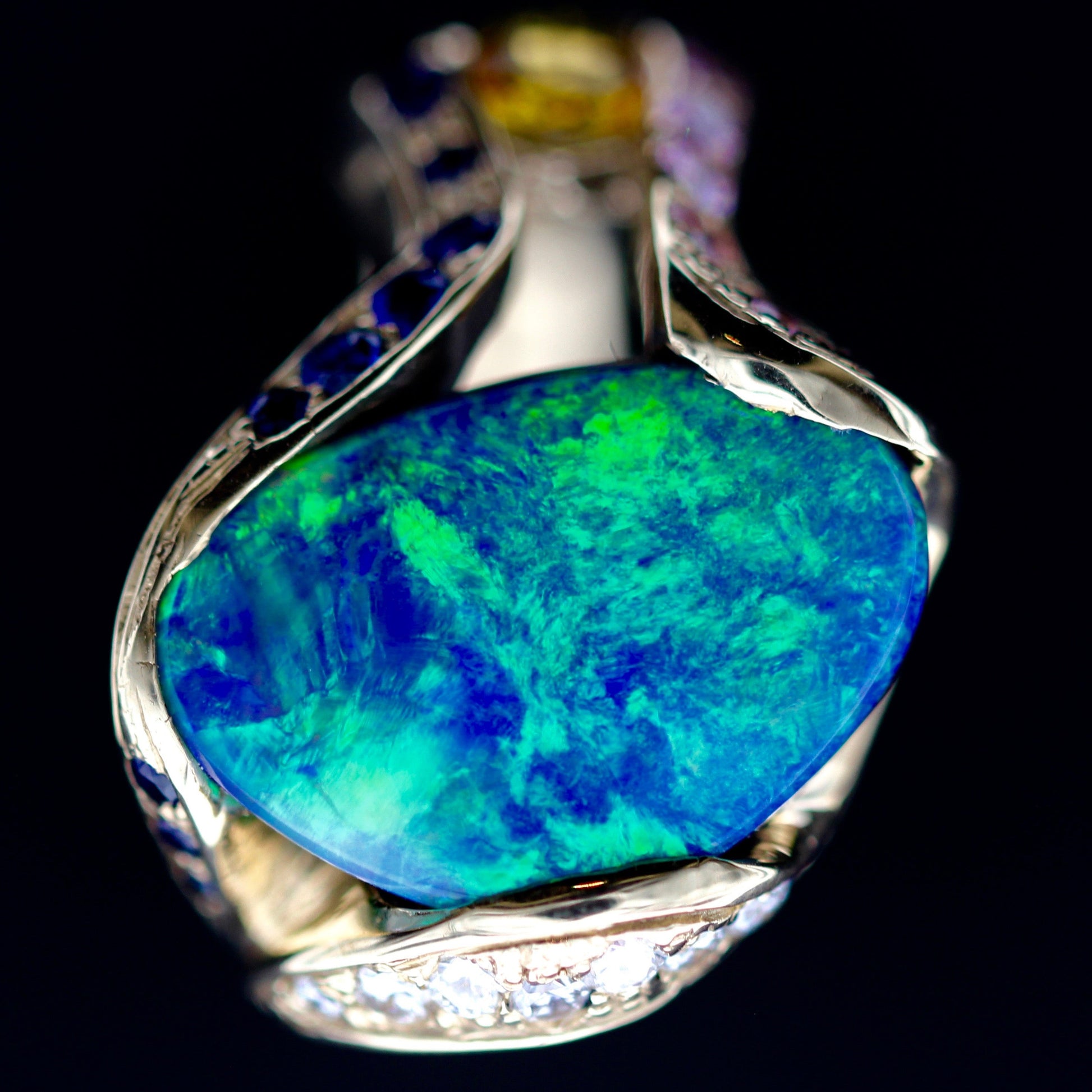 Macro of the freeform Lightning Ridge opal center stone on the 18ct yellow gold cocktail ring with diamond halo details.