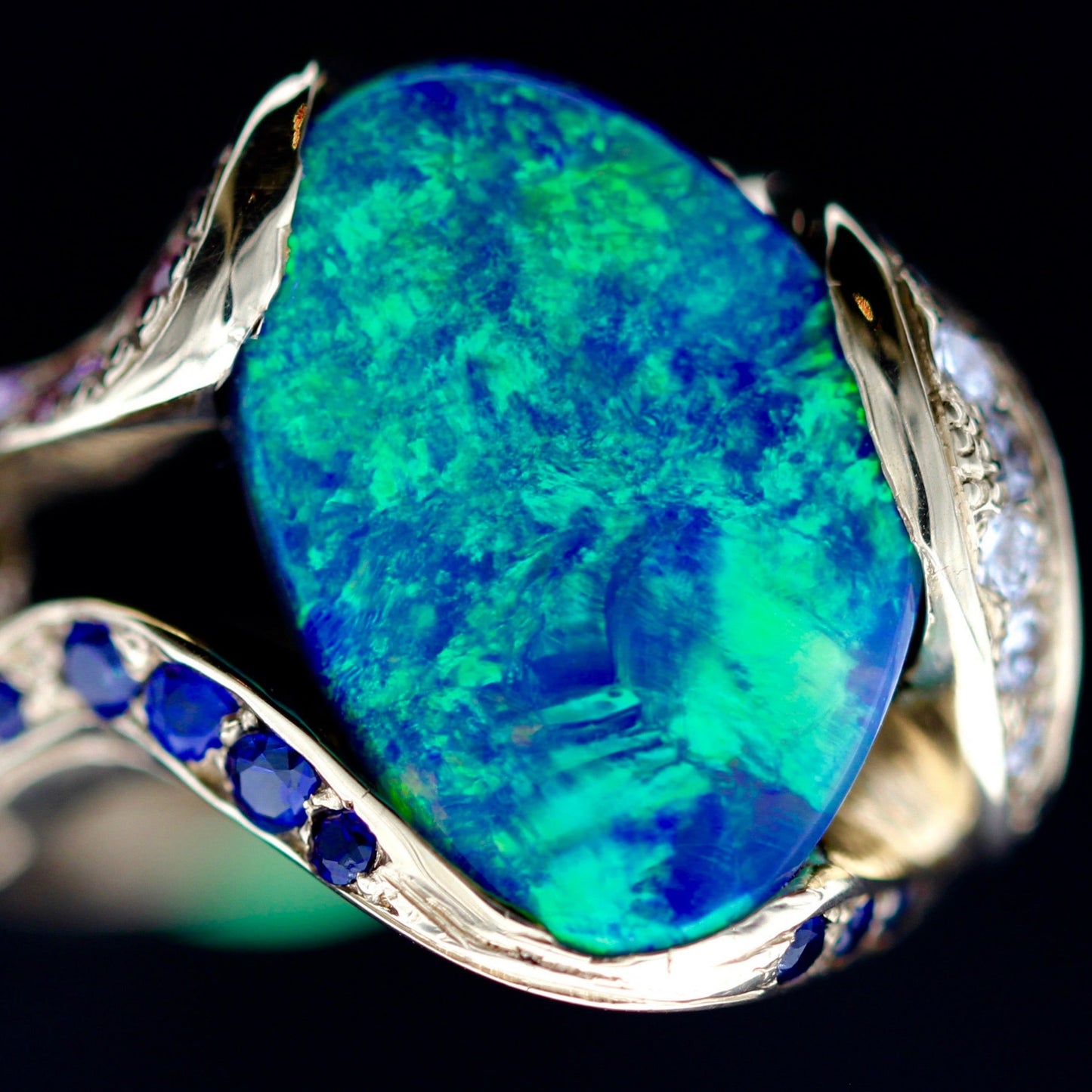 Close-up of lilac and blue sapphire side stones with yellow sapphire accent on the 18ct yellow gold opal cocktail ring.