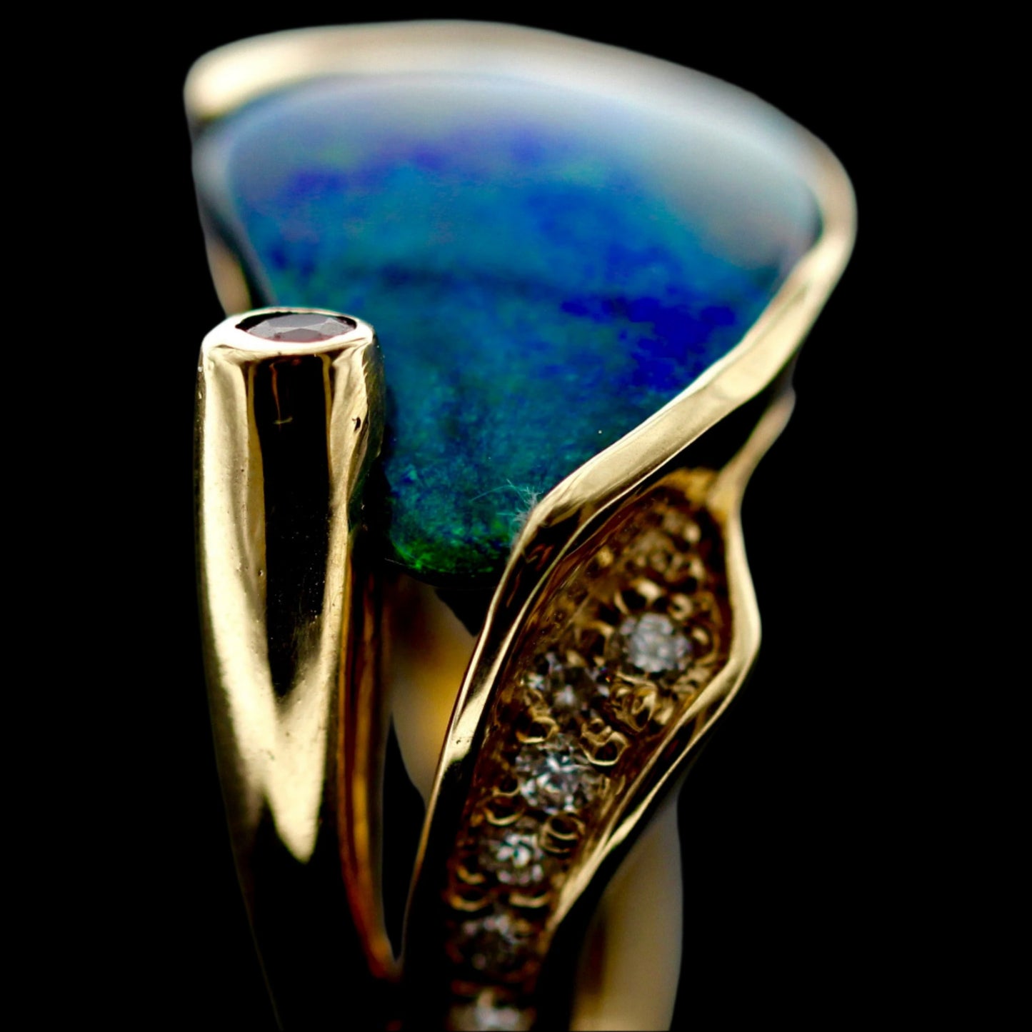 Side profile showing diamond-set shoulder and ruby tube-bezel on the 18ct yellow gold opal cocktail ring.